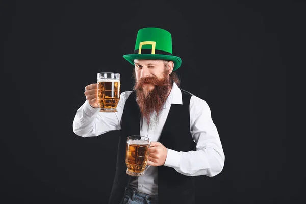 Homem barbudo com copos de cerveja no fundo escuro. Celebração do Dia de São Patrício — Fotografia de Stock