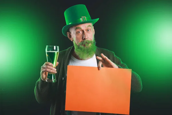 Funny mature man with blank poster and glass of beer on dark background. St. Patrick's Day celebration — 스톡 사진