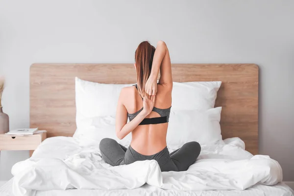 Mulher bonita praticando ioga no quarto — Fotografia de Stock