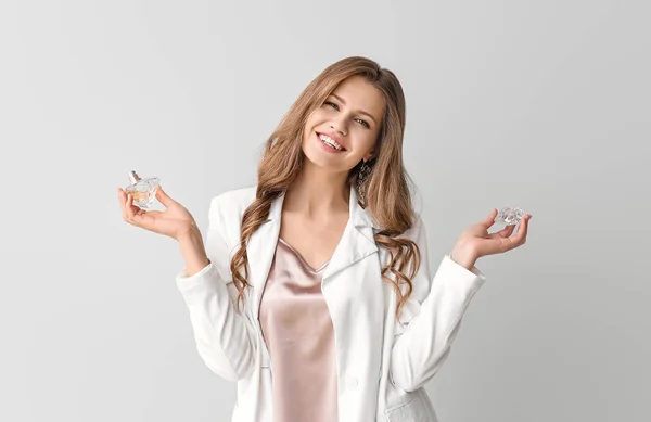 Beautiful young woman with bottle of perfume on light background — Stock Photo, Image