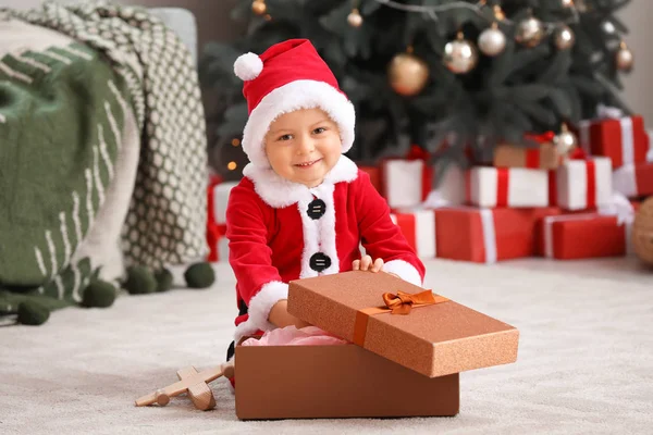 Roztomilý chlapeček v kostýmu Santa a s vánoční dárek doma — Stock fotografie