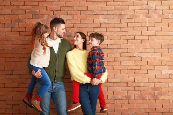 Família feliz em roupas de inverno perto da parede de tijolo — Fotografia de Stock