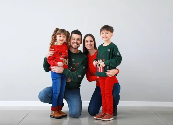 Happy family in Christmas clothes near light wall — Stock Photo, Image