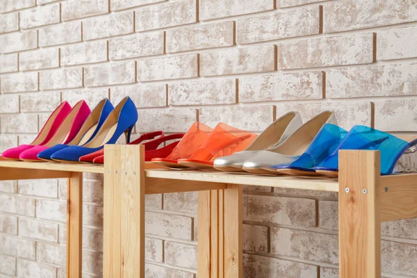 Shelf unit with stylish shoes near brick wall — Stock Photo, Image