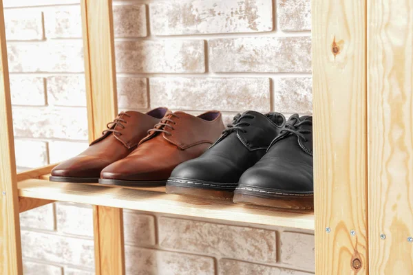 Shelf unit with stylish shoes near brick wall — Stock Photo, Image