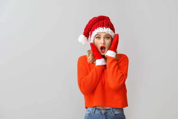 Mujer joven sorprendida en Santa sombrero sobre fondo claro —  Fotos de Stock