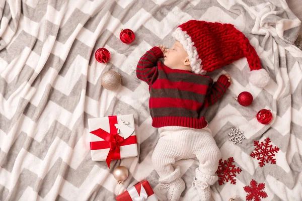 Bebê bonito em chapéu de Papai Noel e com presentes de Natal dormindo em xadrez, vista superior — Fotografia de Stock