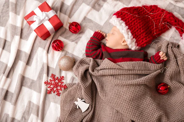 Bebê bonito em chapéu de Papai Noel e com presente de Natal dormindo em xadrez, vista superior — Fotografia de Stock