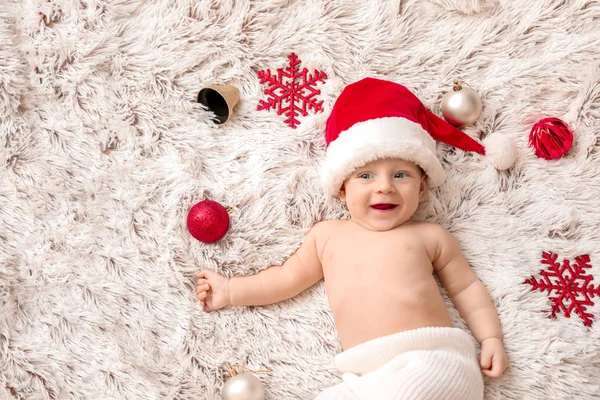 Bebê bonito em chapéu de Papai Noel e com decoração de Natal deitado em xadrez, vista superior — Fotografia de Stock