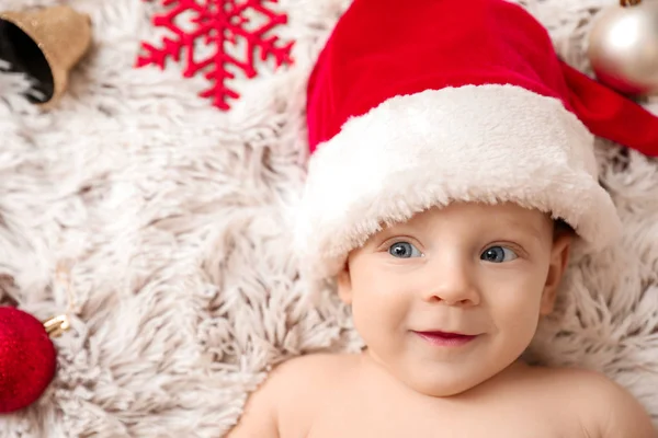 Bonito bebê em chapéu de Papai Noel deitado em xadrez — Fotografia de Stock