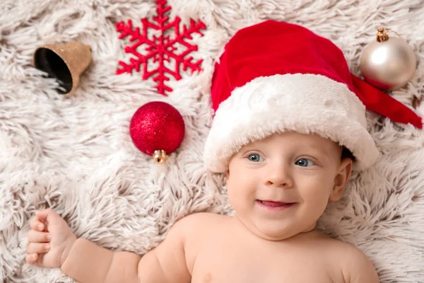 Bonito bebê em chapéu de Papai Noel deitado em xadrez — Fotografia de Stock