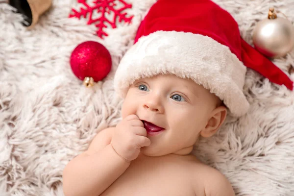 Bonito bebê em chapéu de Papai Noel deitado em xadrez — Fotografia de Stock