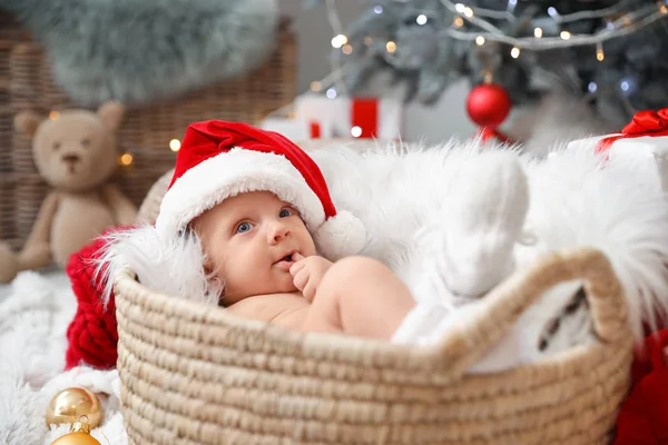 Bebê bonito com chapéu de Papai Noel deitado em cesta em casa — Fotografia de Stock