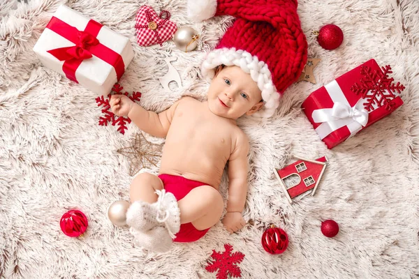 Bebê bonito em chapéu de Papai Noel e com presentes de Natal deitado em xadrez, vista superior — Fotografia de Stock