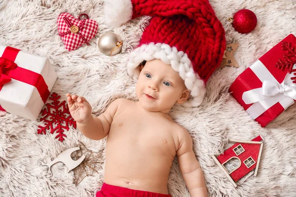 산타클로스 모자를 쓴 작고 귀여운 아기와 플 라디 드 위에 놓인 크리스마스 선물, 맨 위 뷰 — 스톡 사진