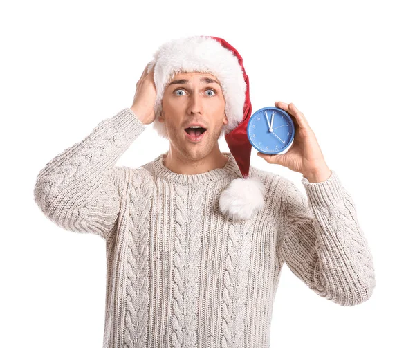 Verrassende jongeman met kerstmuts en wekker op witte achtergrond. Kerst countdown concept — Stockfoto