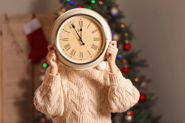 Νεαρή γυναίκα με ρολόι στο δωμάτιο. Χριστούγεννα αντίστροφη μέτρηση έννοια — Φωτογραφία Αρχείου