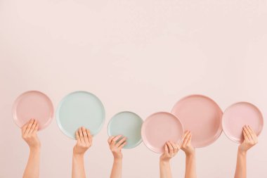 Renk arkaplanında farklı temiz plakalara sahip eller