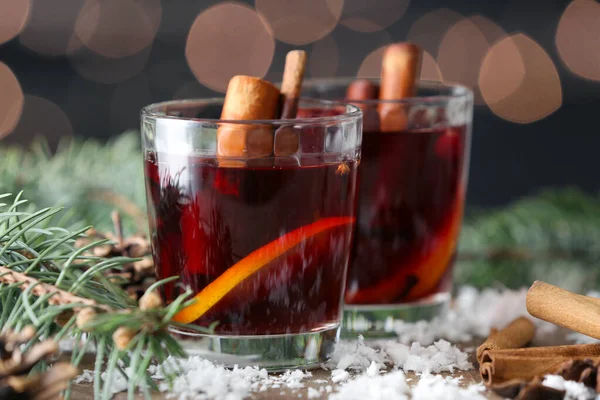 Glasses of tasty mulled wine, fir branches and snow on table — Stock Photo, Image