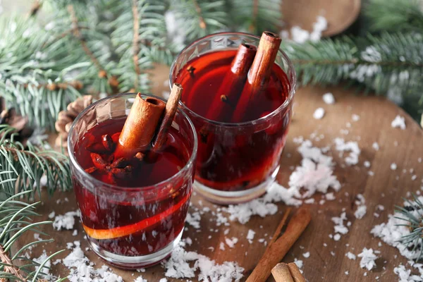 Glasses of tasty mulled wine, fir branches and snow on table — Stock Photo, Image