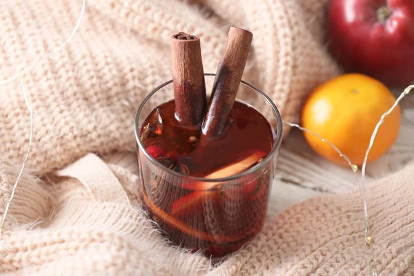 Glass of tasty mulled wine and warm plaid on table — Stock Photo, Image