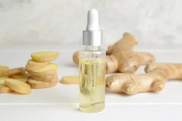 Bottle with ginger essential oil on white table — Stock Photo, Image