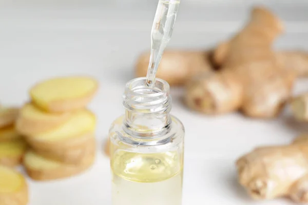 Dripping of ginger essential oil into bottle on table, closeup — Stock Photo, Image