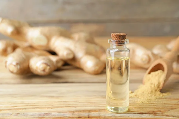 Bottle with ginger essential oil on wooden table — Stock Photo, Image