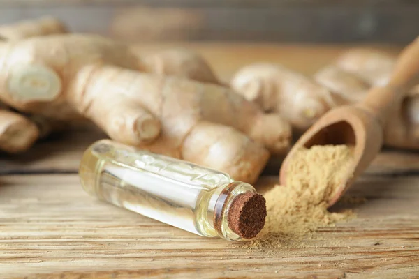 Bottle with ginger essential oil on wooden table — Stock Photo, Image