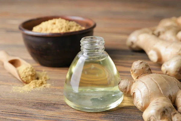 Bottle with ginger essential oil on wooden table — Stock Photo, Image