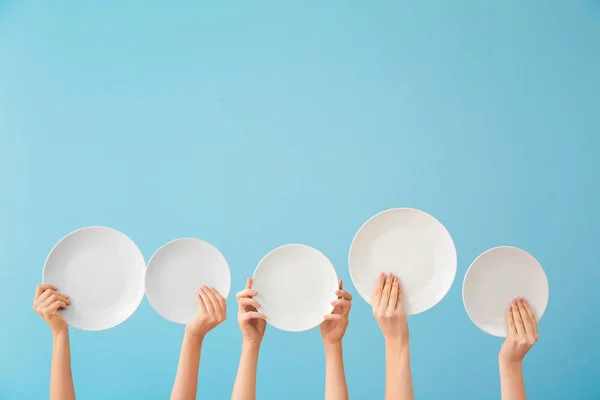 Hands with clean plates on color background — Stock Photo, Image