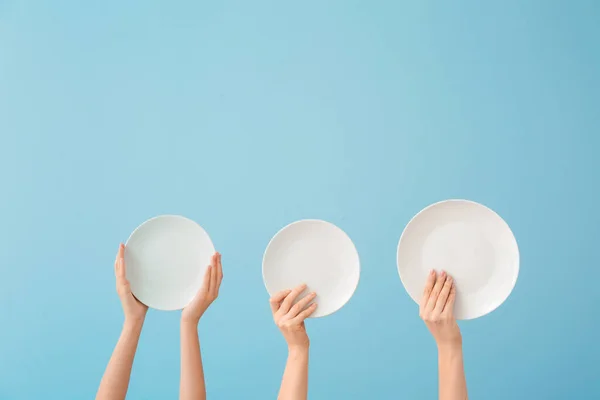 Hands with clean plates on color background — Stock Photo, Image