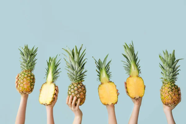 Руки с сочными ананасами на цветном фоне — стоковое фото