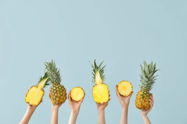 Ręce z soczystymi ananasami na tle koloru — Zdjęcie stockowe