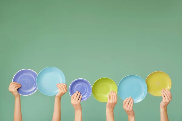 Hände mit verschiedenen sauberen Platten auf farbigem Hintergrund — Stockfoto