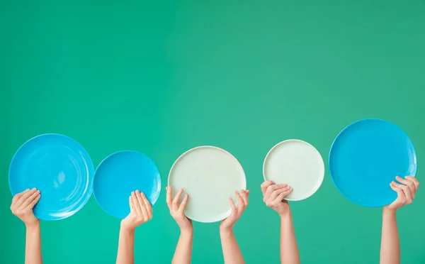 Hände mit verschiedenen sauberen Platten auf farbigem Hintergrund — Stockfoto