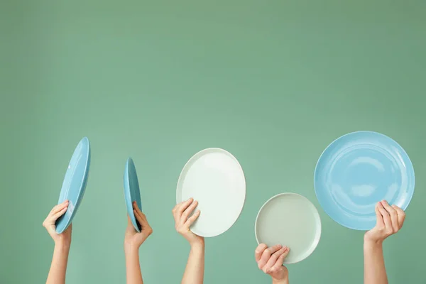 Hände mit verschiedenen sauberen Platten auf farbigem Hintergrund — Stockfoto