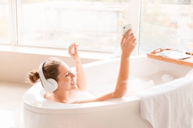 Güzel genç bayan evde banyo yaparken müzik dinliyor.
