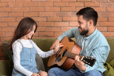 Küçük kızı ve babası evde gitar çalıyorlar.