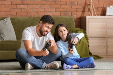 Babası ve küçük kızı evde video oyunu oynuyorlar.