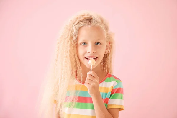 Cute little girl with lollipop on color background — Stock Photo, Image