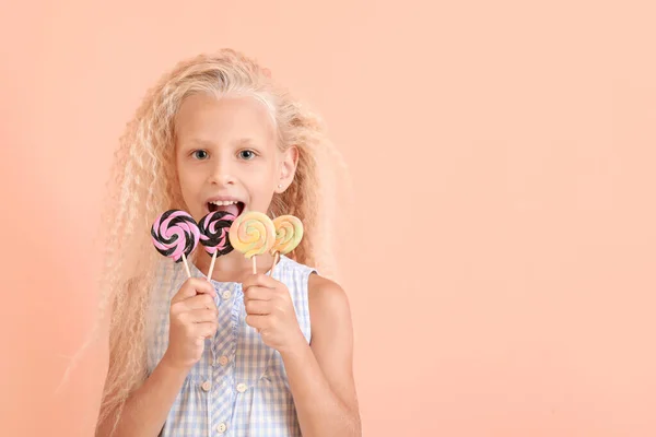 Cute little girl with lollipops on color background — Stock Photo, Image