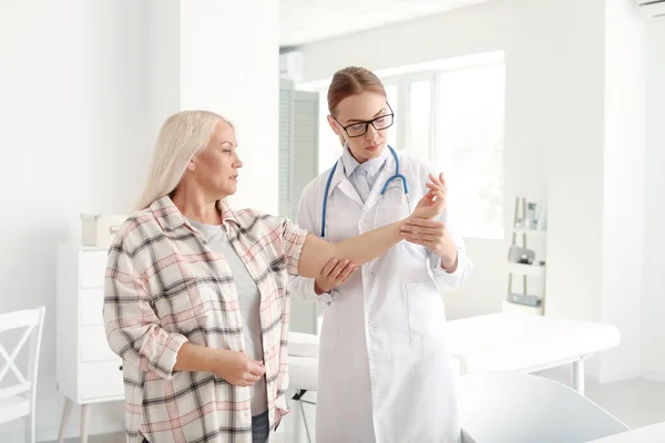 Arzt untersucht reife Frau mit Gelenkschmerzen in Klinik — Stockfoto