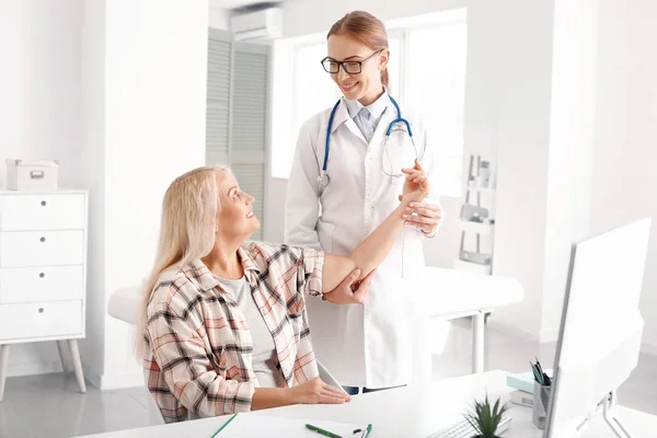 Arzt untersucht reife Frau mit Gelenkschmerzen in Klinik — Stockfoto