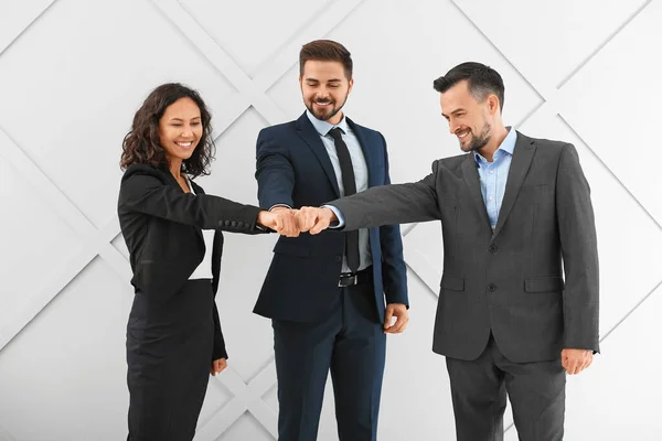 Porträt junger Geschäftsleute, die vor grauem Hintergrund die Hände zusammenlegen — Stockfoto