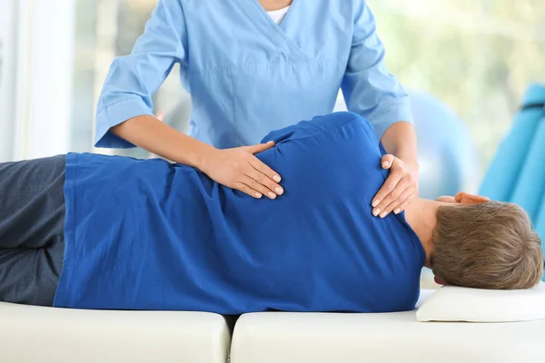 Fisioterapeuta trabajando con paciente masculino en centro de rehabilitación — Foto de Stock