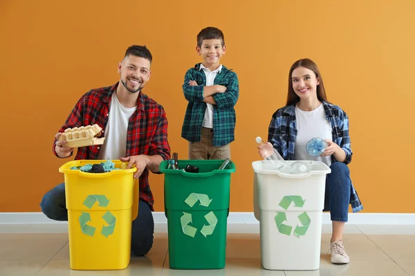 Familia con contenedores para basura sobre fondo de color. Concepto de reciclaje —  Fotos de Stock