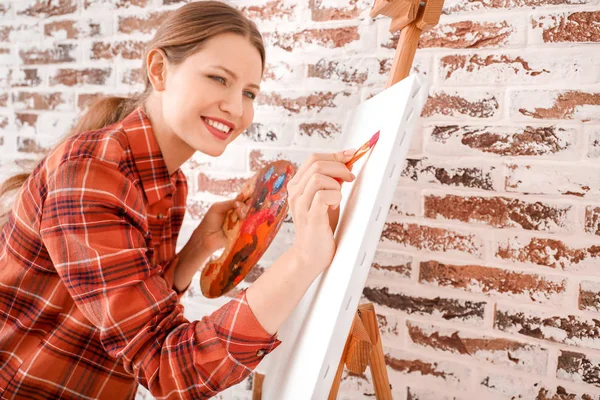 Young female artist against brick wall — Stock Photo, Image