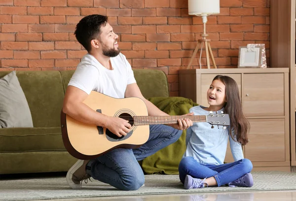 Little daughter and her father playing guitar at home — Stock Photo, Image