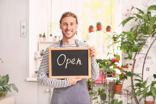 Portrait of male florist holding chalkboard with text OPEN in shop — Stock Photo, Image